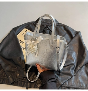 Détail du sac seau argenté métallisé avec breloque cœur et texture en cuir PU plissé