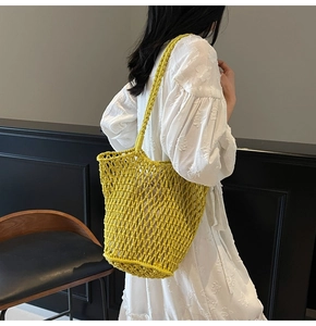 Detail view of bright yellow hollow knit tote bag worn by model in summer style