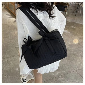 Detail showing black nylon pleated bucket bag with decorative ribbon bows and zipper