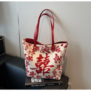 Detail of red floral canvas tote with leather handles on minimalist backdrop