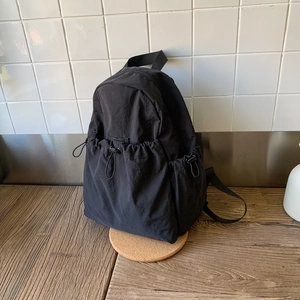 Detail of black nylon mini backpack with drawstring pocket and wrinkled fabric texture