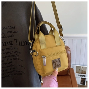 Detail of a bright yellow waterproof nylon crossbody bag with silver zippers and strap
