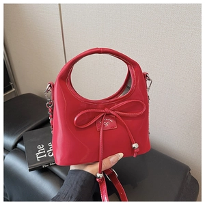 Détail d'un sac à main en cuir verni rouge avec cordon à nœud et bandoulière chaîne