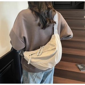Detailed view of beige nylon crescent bag with double zippers and rope pullers