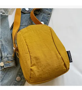Détail du mini sac bandoulière jaune en nylon texturé avec sangle griffée