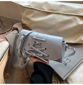 Detail of light blue PU leather bag featuring cross-lacing and bow decoration