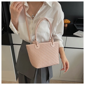 Detailed close-up of pink woven V-pattern straw bag with adjustable shoulder strap