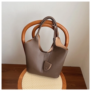 Detailed view of dark brown pebbled leather texture on a stylish bucket tote bag