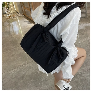 Detail of black pleated nylon bucket bag featuring a decorative knotted shoulder strap