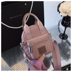 Detail of waterproof nylon crossbody bag in lotus pink with wide fabric strap and silver hardware