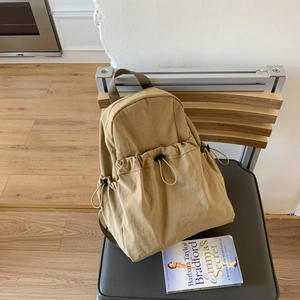 Detail of khaki nylon backpack with drawstring pockets and durable reinforced handle
