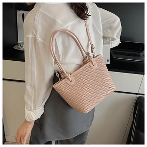 Pink woven leather bucket bag worn by a model in a professional office setting