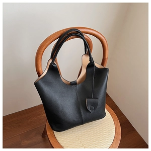 Close-up of black pebbled leather bucket bag with V-shaped opening on a wooden chair