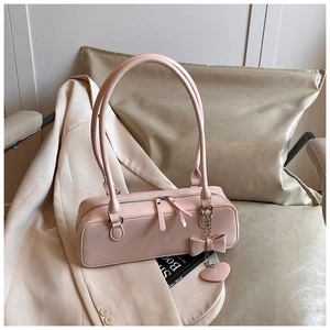 Detailed shot of pink baguette handbag featuring double zippers and a heart charm on a blazer