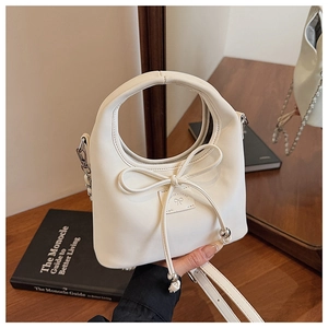 Détail du sac à main blanc en simili cuir avec nœud décoratif, chaîne et clous de fond