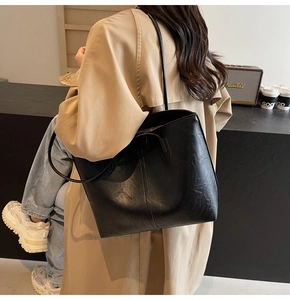 Detail of high-capacity black tote bag in textured PU leather for office commuting
