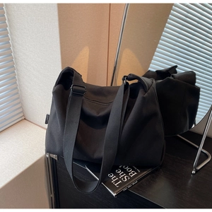 Detail of durable black canvas tote showing adjustable wide strap and metallic buckle