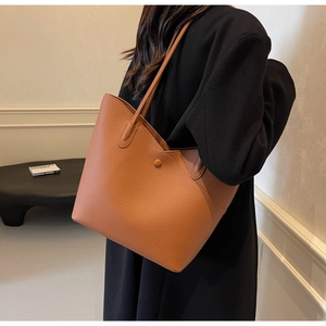Brown lychee leather tote bag with long shoulder straps shown on a model for scale