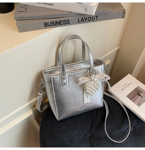 Détail du sac argenté plissé avec breloque cœur en perle et décoration nœud en dentelle