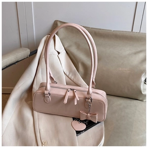 Detail of light pink PU leather baguette bag with bow and heart charms decoration