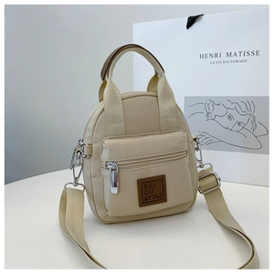 Detail of beige waterproof nylon crossbody bag with front zipper pocket and leather label