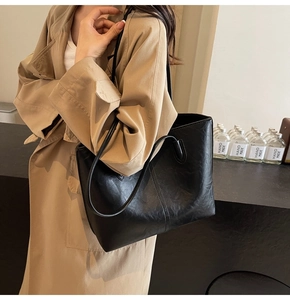 Detail of a vintage black leather tote bag with vertical stitching and smooth oil finish