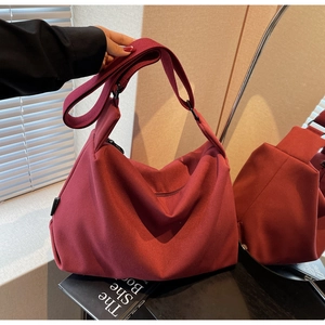 Detail view of burgundy canvas tote bag with wide adjustable strap and side zipper pocket