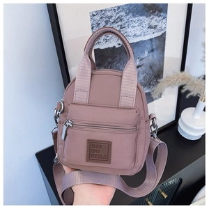 Close-up of pink waterproof nylon crossbody bag with durable zippers and logo detail