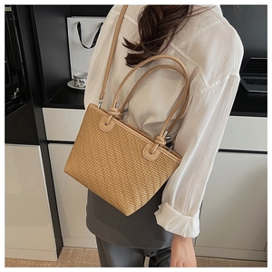 Detailed close-up of the V-shaped woven texture and silver hardware on a beige tote bag