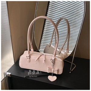Detail of light pink leather baguette bag featuring a bow and heart metal charm