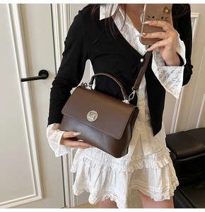 Detail of vintage square handbag in dark brown leather with a silver rotating metal lock