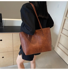 Detail of vintage brown tote bag texture and slender shoulder straps worn by model