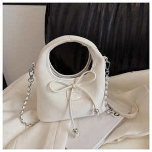 Détail du sac demi-lune crème avec nœud décoratif et bandoulière en chaîne argentée