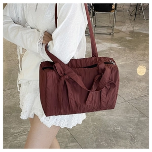 Detail of burgundy pleated nylon tote bag featuring stylish ribbon bow and long straps