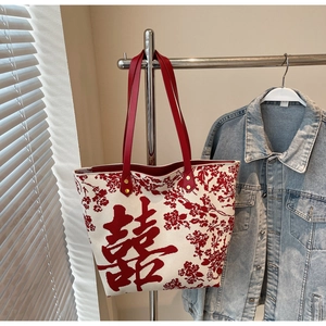 Close-up of woven tote bag featuring red leather handles and traditional Chinese Xi character