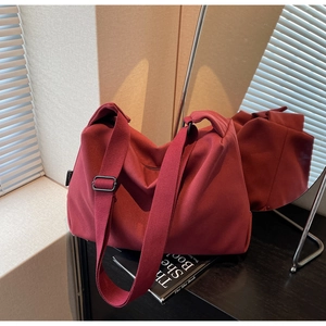 Deep red canvas tote bag detail featuring thick strap and matte metal adjustment buckle