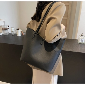 Detailed macro view of black lychee-textured leather tote bag with elegant shoulder strap