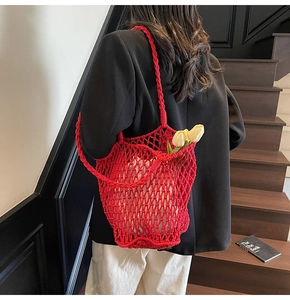 Detail of red hollow knit tote bag with mesh design carried on a modern staircase