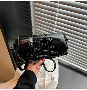 Detail of black oil wax leather bag with lace-up eyelets and sleek baguette style shape
