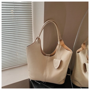 Detail view of large beige hobo bag showing pebble leather texture and a matching leather charm