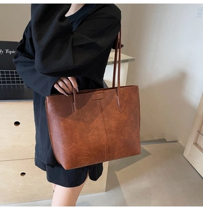 Detail of a large brown vintage tote bag featuring vertical stitching and reinforced handles