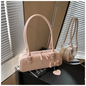 Pink baguette bag with dual zippers, bow charm, and heart pendant in a mirror display