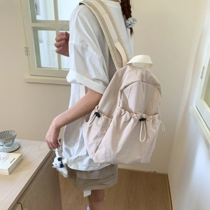 Detail of light beige nylon backpack with drawstring side pocket and wide strap