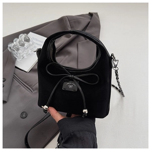 Détail du mini sac à main en daim noir avec nœud en cuir verni et plaque en métal