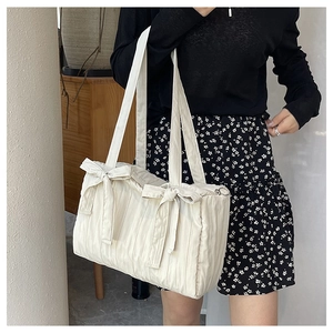 Detail of cream pleated nylon tote with quilted cloud texture and bow accents