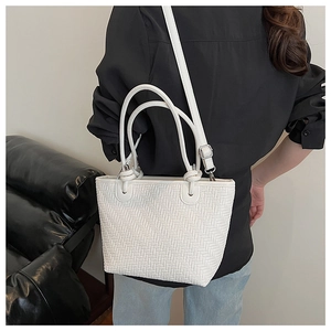 Detailed close-up of white woven tote bag texture with adjustable shoulder strap and handles