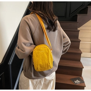 Détail de la sacoche en nylon jaune avec bandoulière réglable portée par un mannequin
