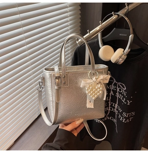 Détail du sac cabas argenté métallisé avec nœud en dentelle, perle et bandoulière réglable