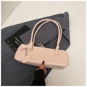 Detail view of pink baguette bag with leather bow and heart charm on grey blazer