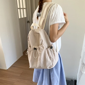 Minimalist beige nylon backpack featuring drawstring closure and side adjustment buckles